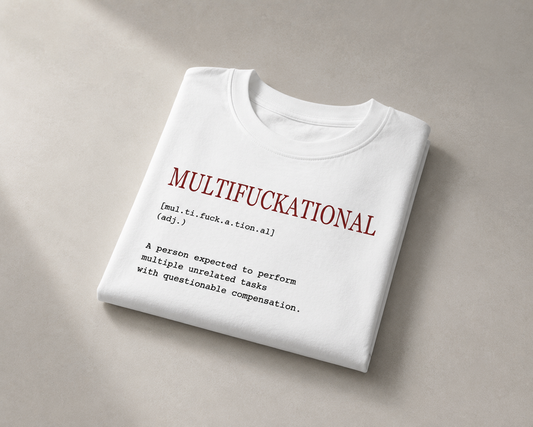 A folded white t-shirt with a humorous dictionary-style definition printed on the front, displayed on a neutral beige background.