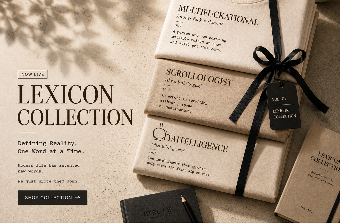 A styled flat-lay of a book or booklet titled 'Lexicon Collection' wrapped in a black ribbon with a black hangtag, alongside other matching cream-colored booklets with printed dictionary-style definitions. A coffee cup, a notebook, and leaf shadows are visible on a light beige surface.